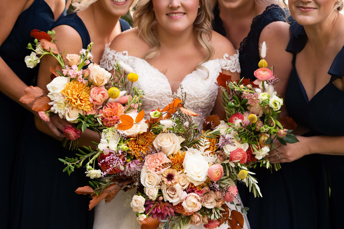 Ottawa wedding photography showing the closeup details of a bride and bridesmaids' bouquets with orange, coral and white flowers