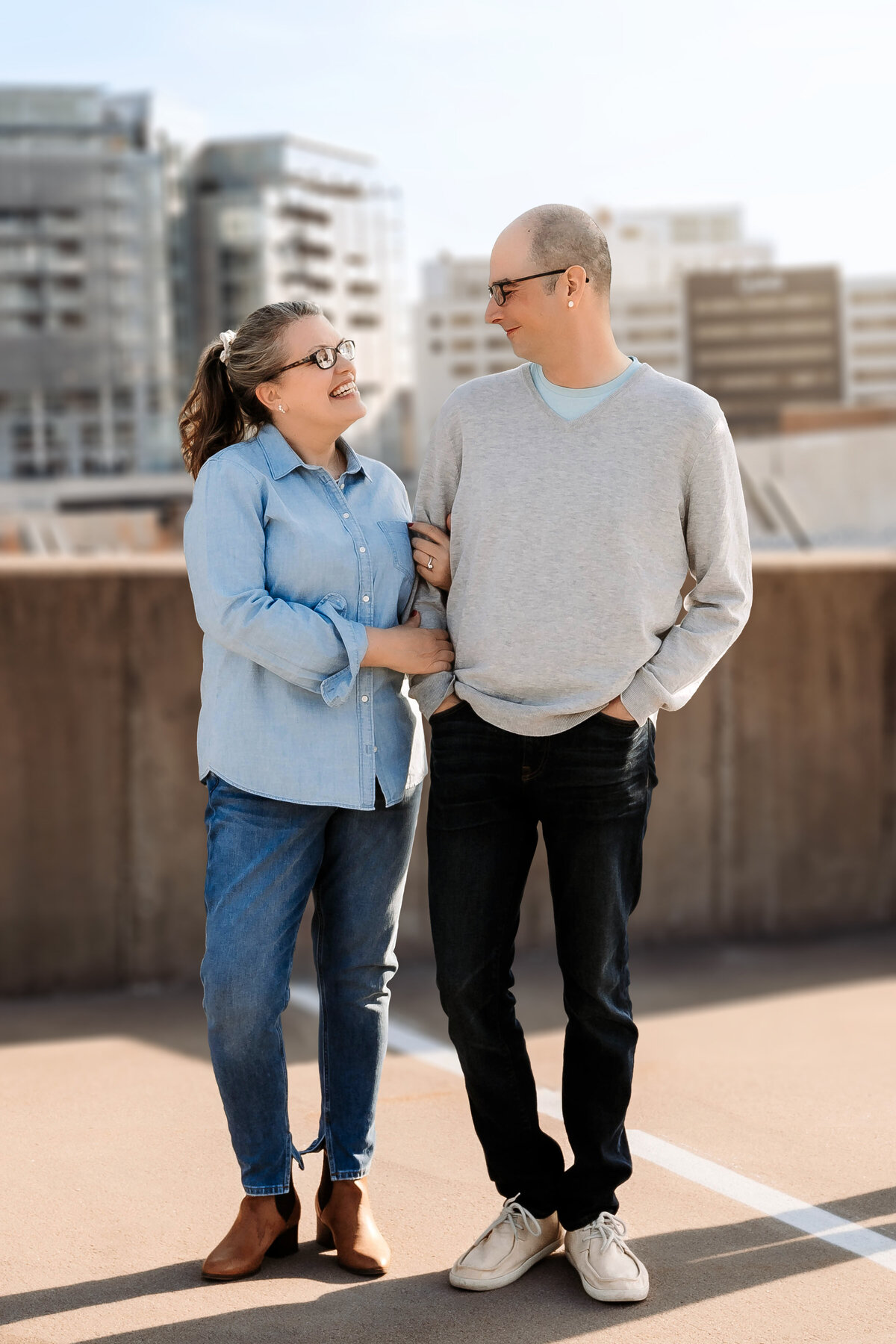 This couple wraps arms while posing on top of a parking garage in Iowa City.