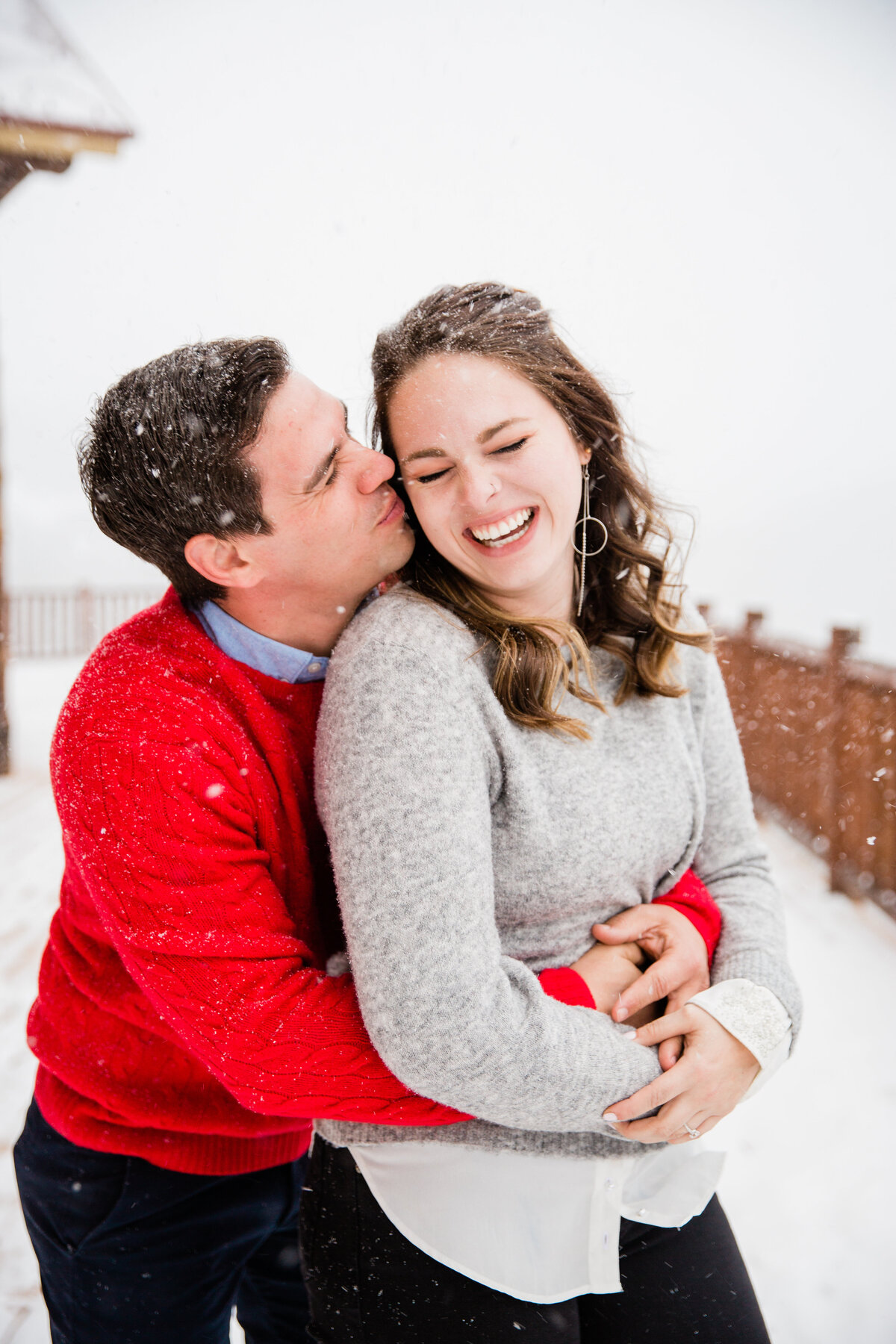 A newly engaged couple are embraced in a tight hug during a whiteout snowstorm