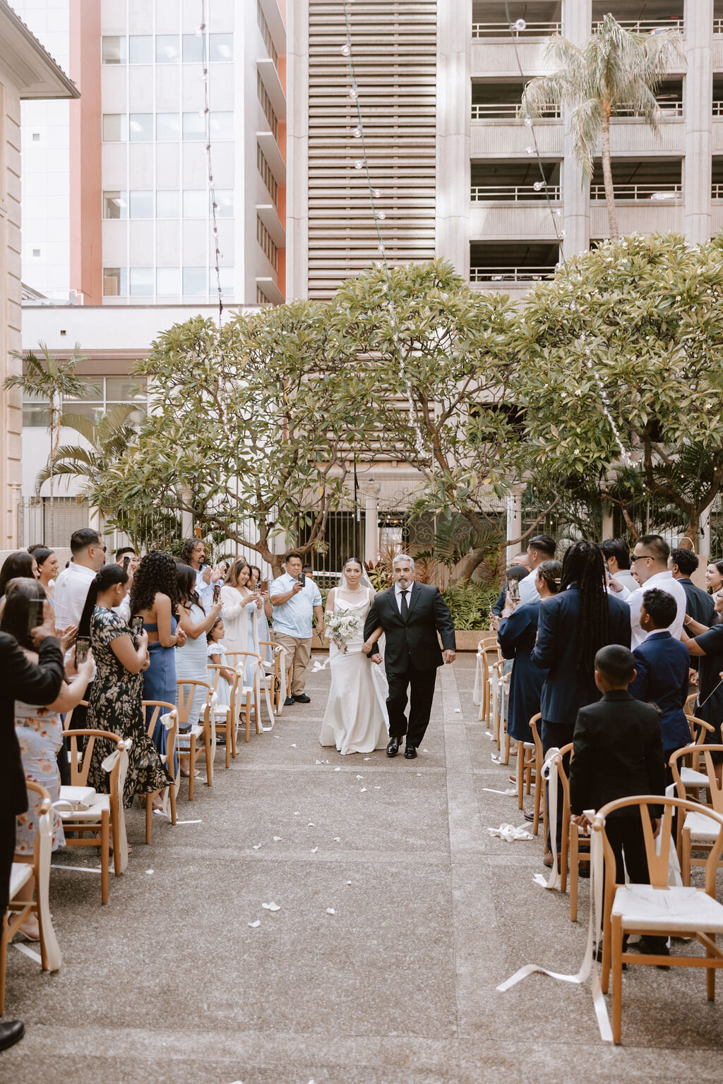 Bride and father walking down aisle while guests stand