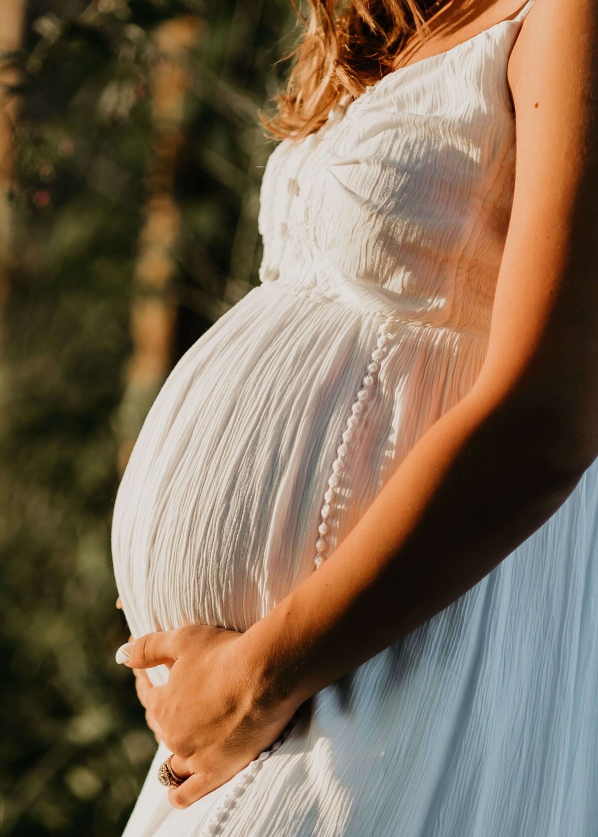 A pregnant woman in a white dress captured by a Pittsburgh maternity photographer.