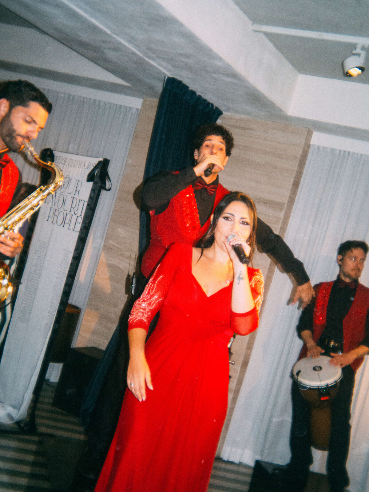 Female vocalist singing while saxophonist plays during wedding party

