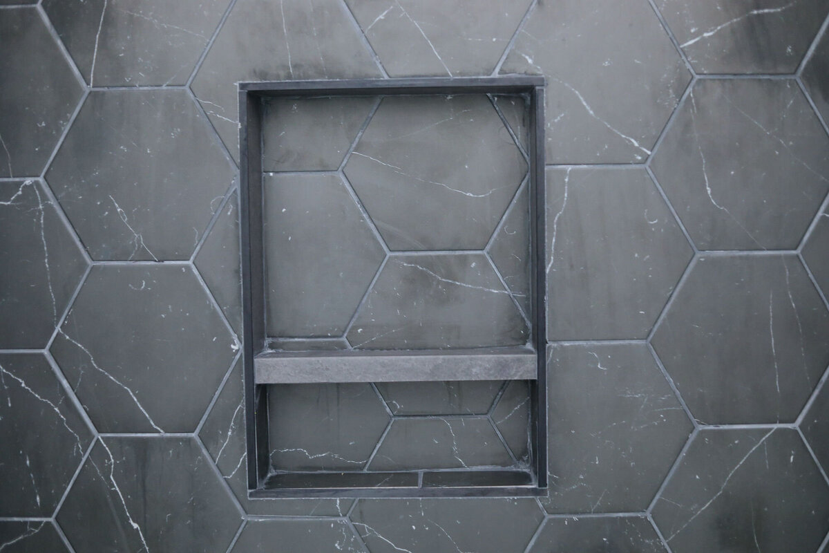 Black and gray hexagon tile in bathroom niche