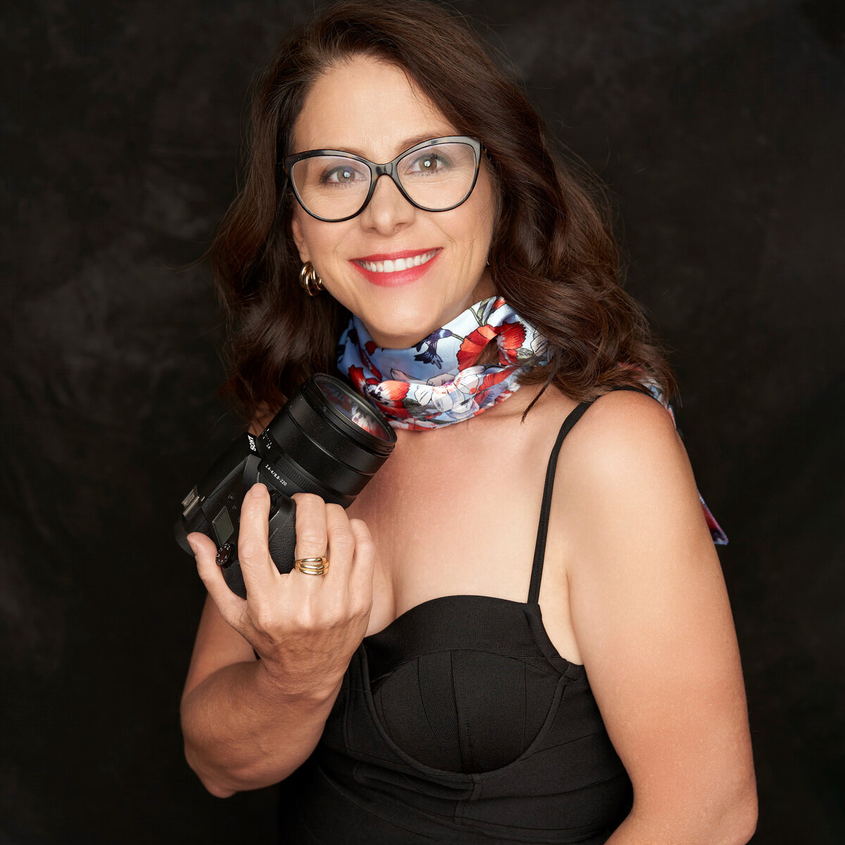 Wendy Adamson, portrait photographer in Prosper, TX, holding a camera.