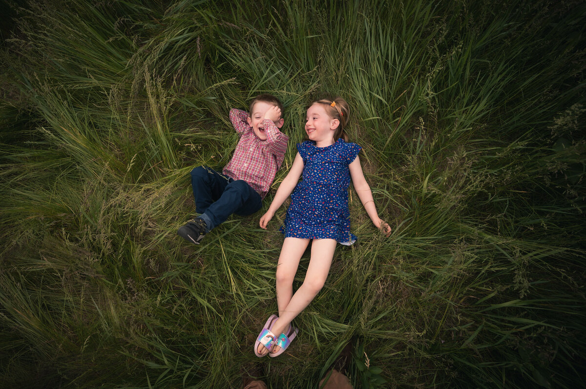 Two kids laying in grass laughing