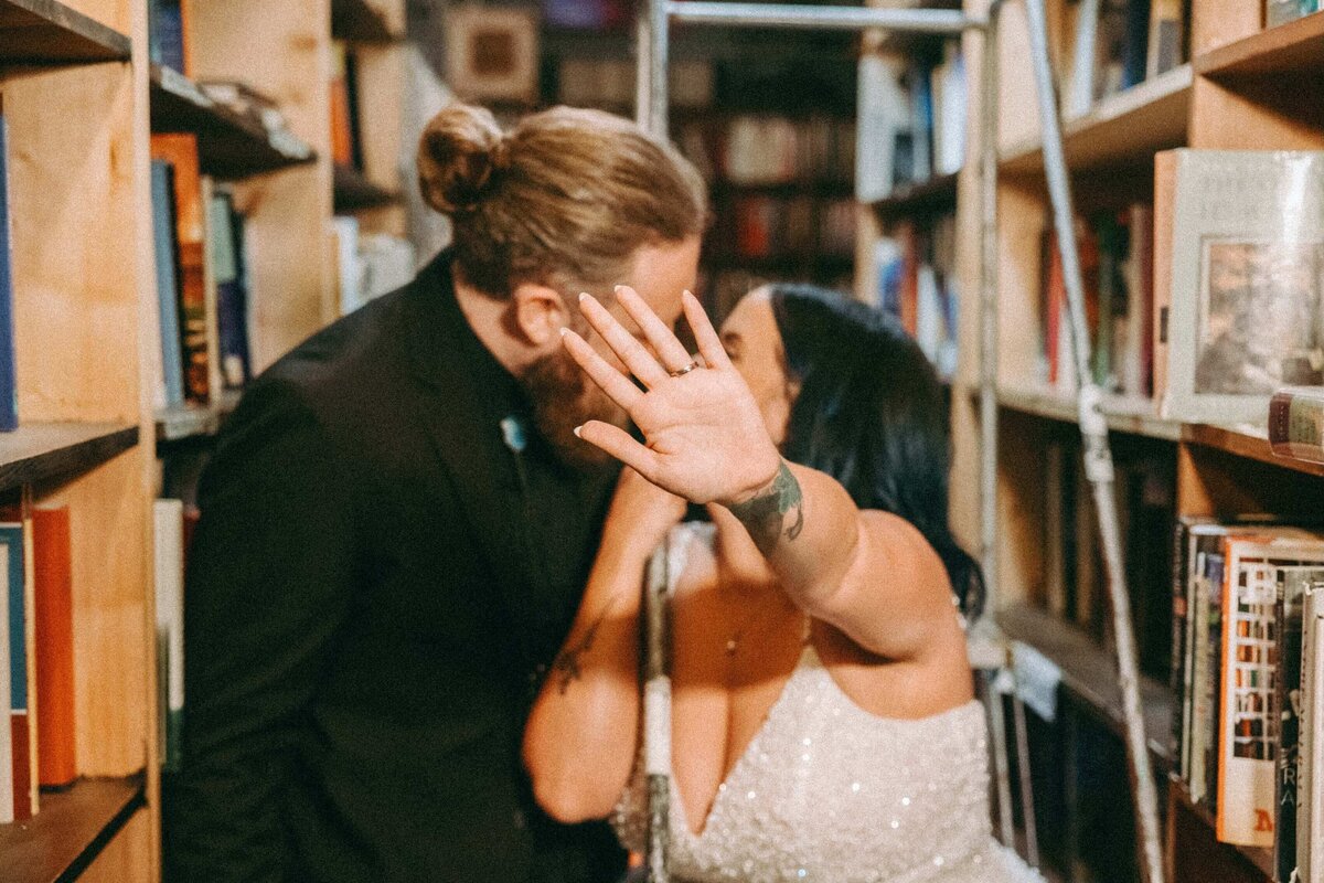 Couple Kissing in Bookstore, Hand Hiding Faces