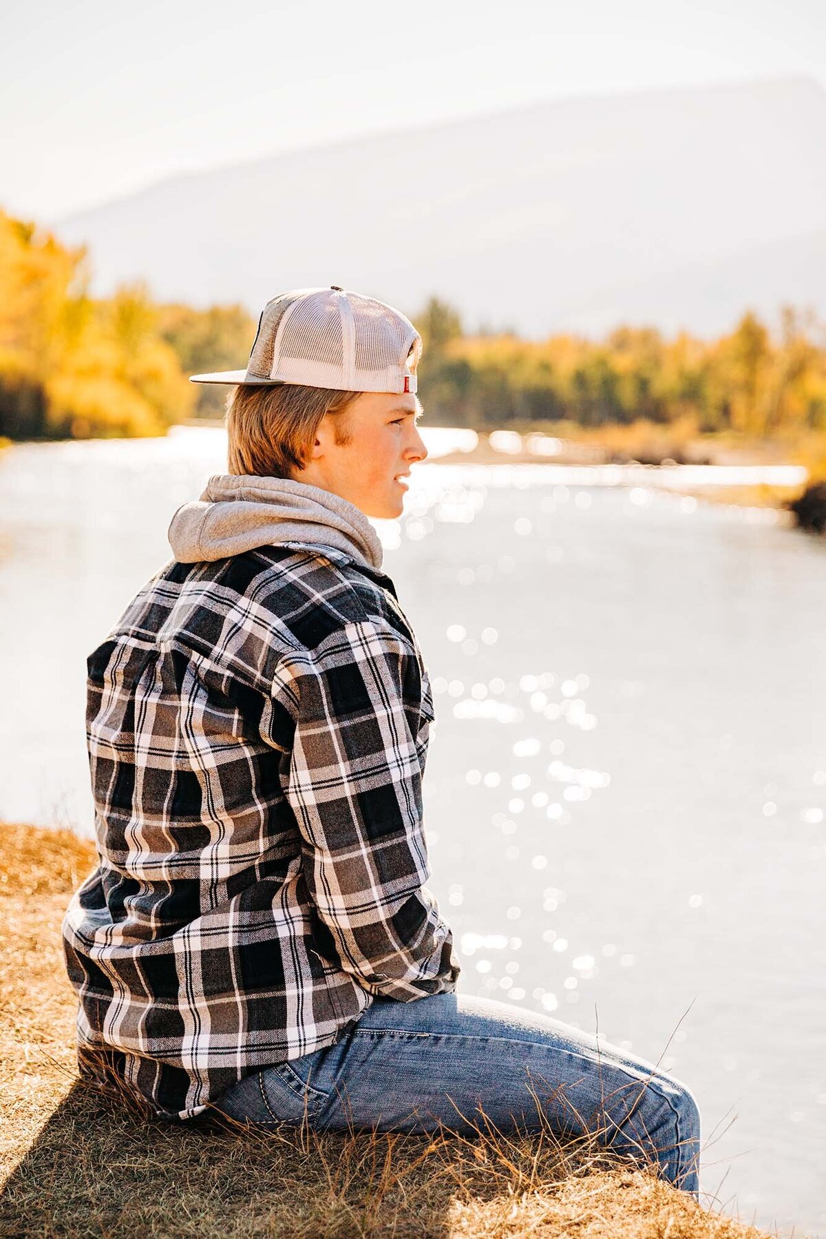 Senior photo of boy sitting on bank of Bitterroot River, Hamilton, MT