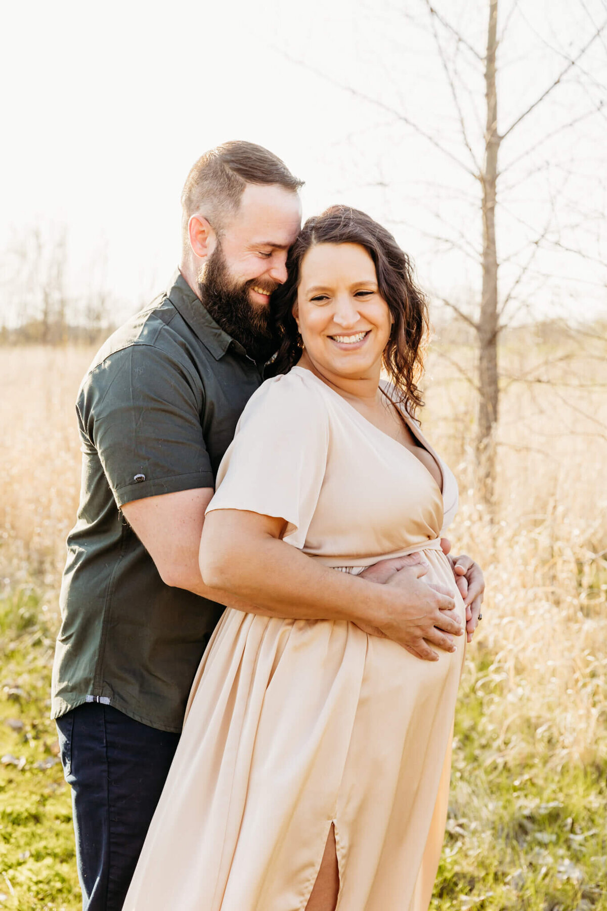 adorable couple laughing as they rest their hands on the pregnant woman's baby bump in Appleton