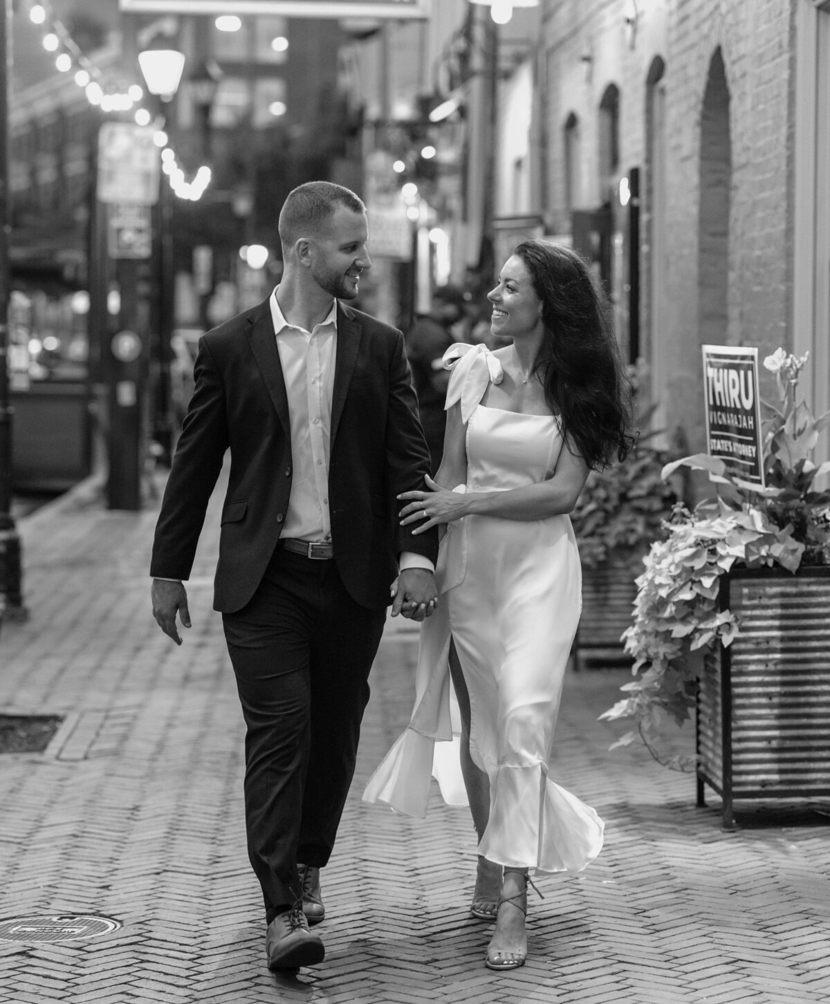 classy man and woman engagement session holding arms city streets in baltimore maryland