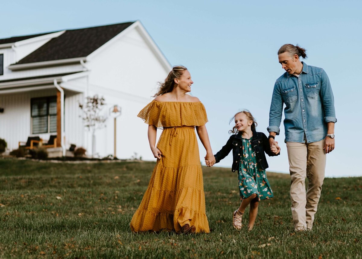A family from Pittsburgh, captured holding hands in front of a farmhouse by a photographer.