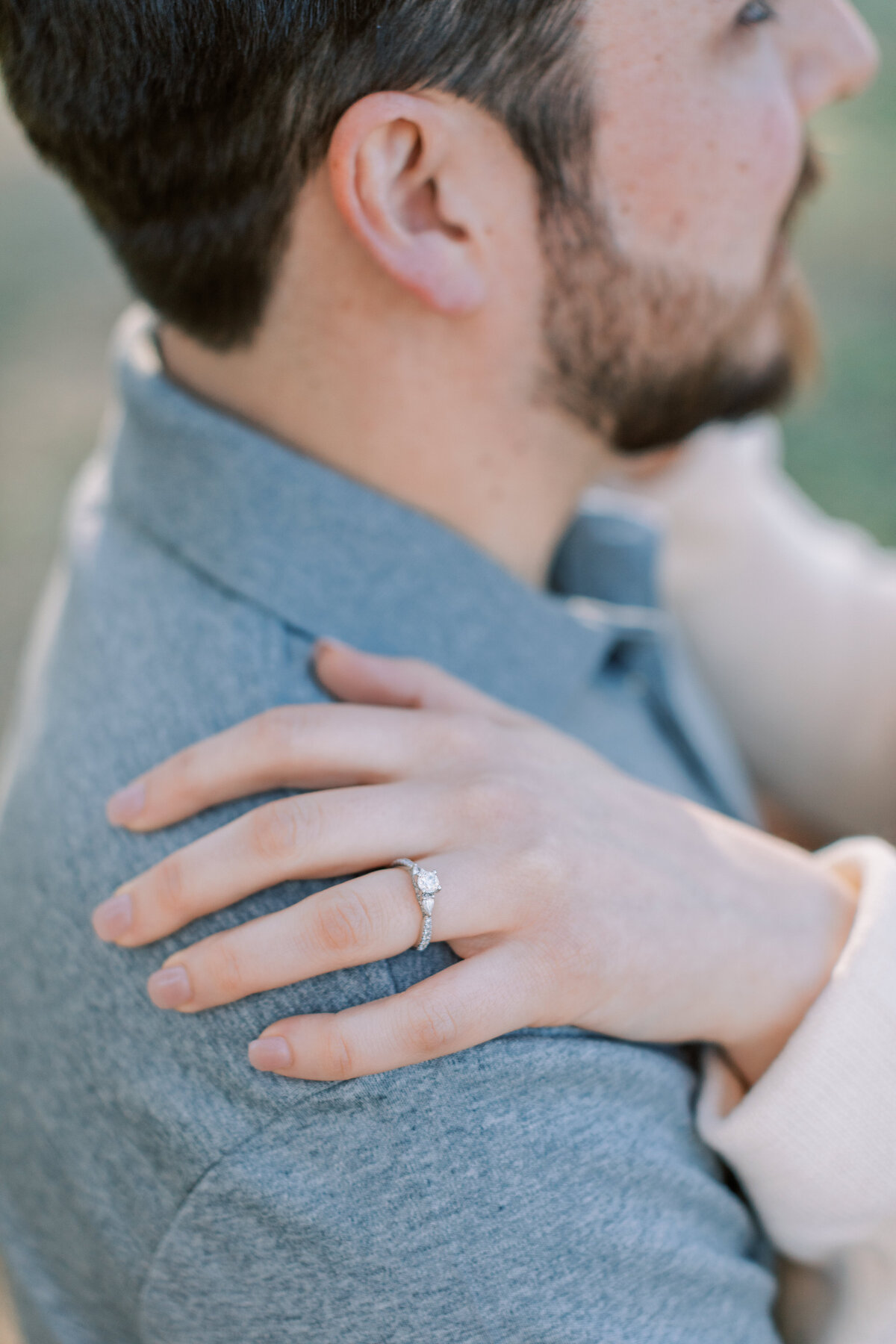 A classic engagement ring is worn.