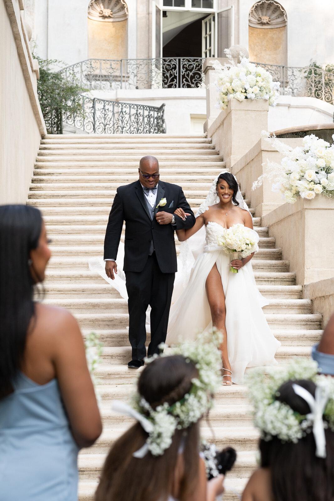 A bride being walked down the steps by her father at the Swan House in Atlanta, GA