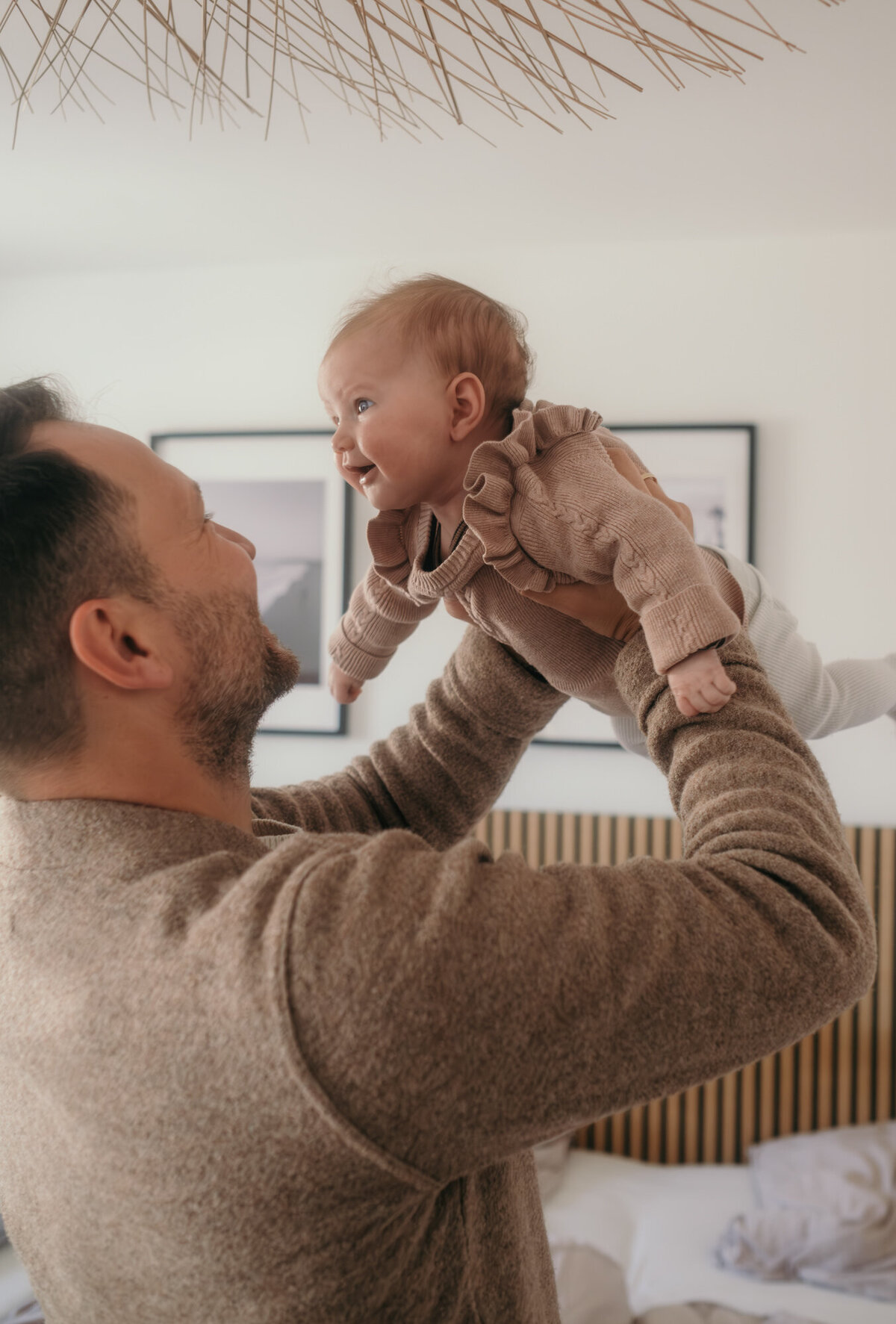 Dad lifts baby in the air, having fun.