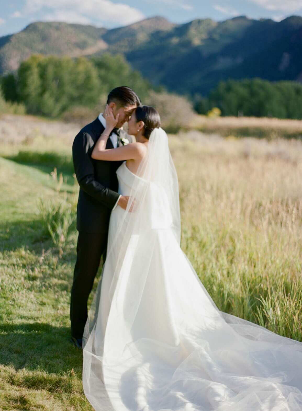 Bride and groom share an intimate moment of embrace among the natural grasses at their Aspen Meadows Resort wedding venue.