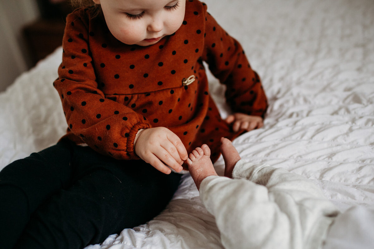 new big sister checking out little baby sisters toes