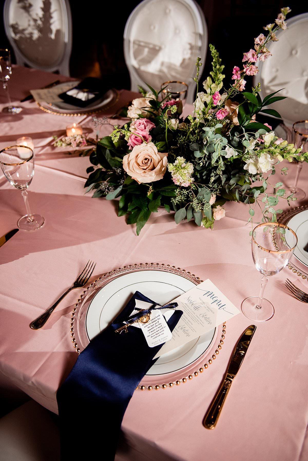 Glass chargers with gold detailing, clear dishes on top and navy napkins