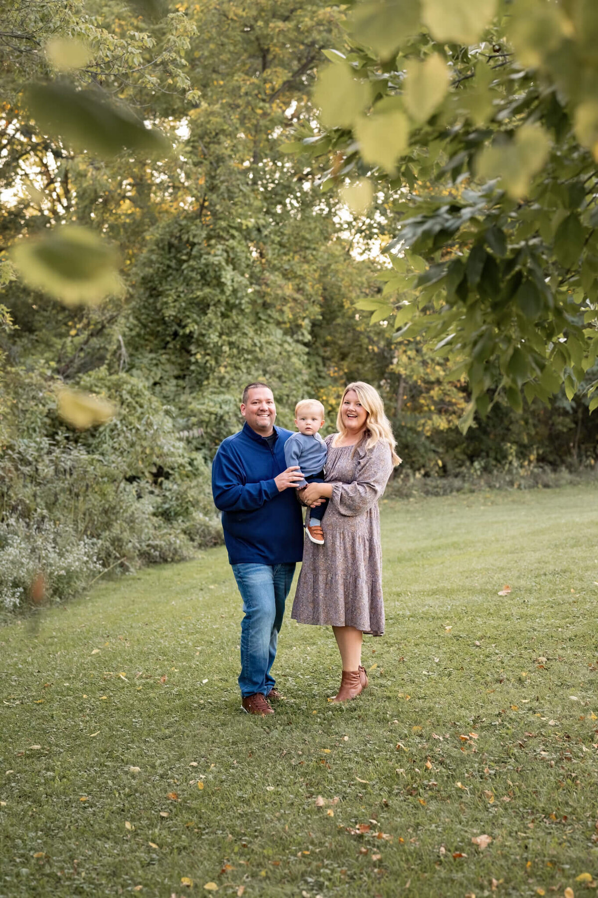 parents holding one year old son in nature
