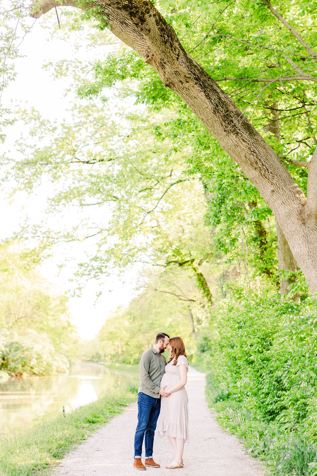 a pregnant woman hugging her husband under a tree