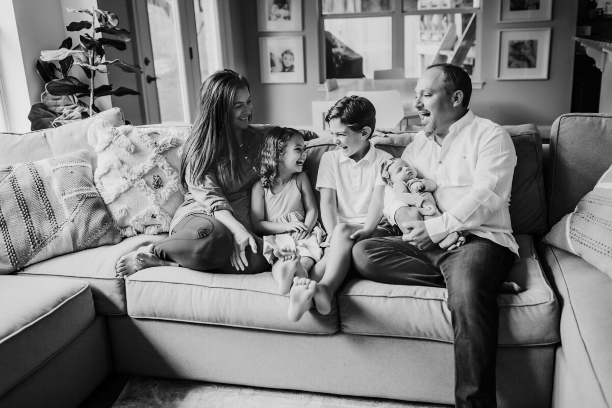 Newborn Photography, Black and white photo of family sitting together snuggling on the couch.