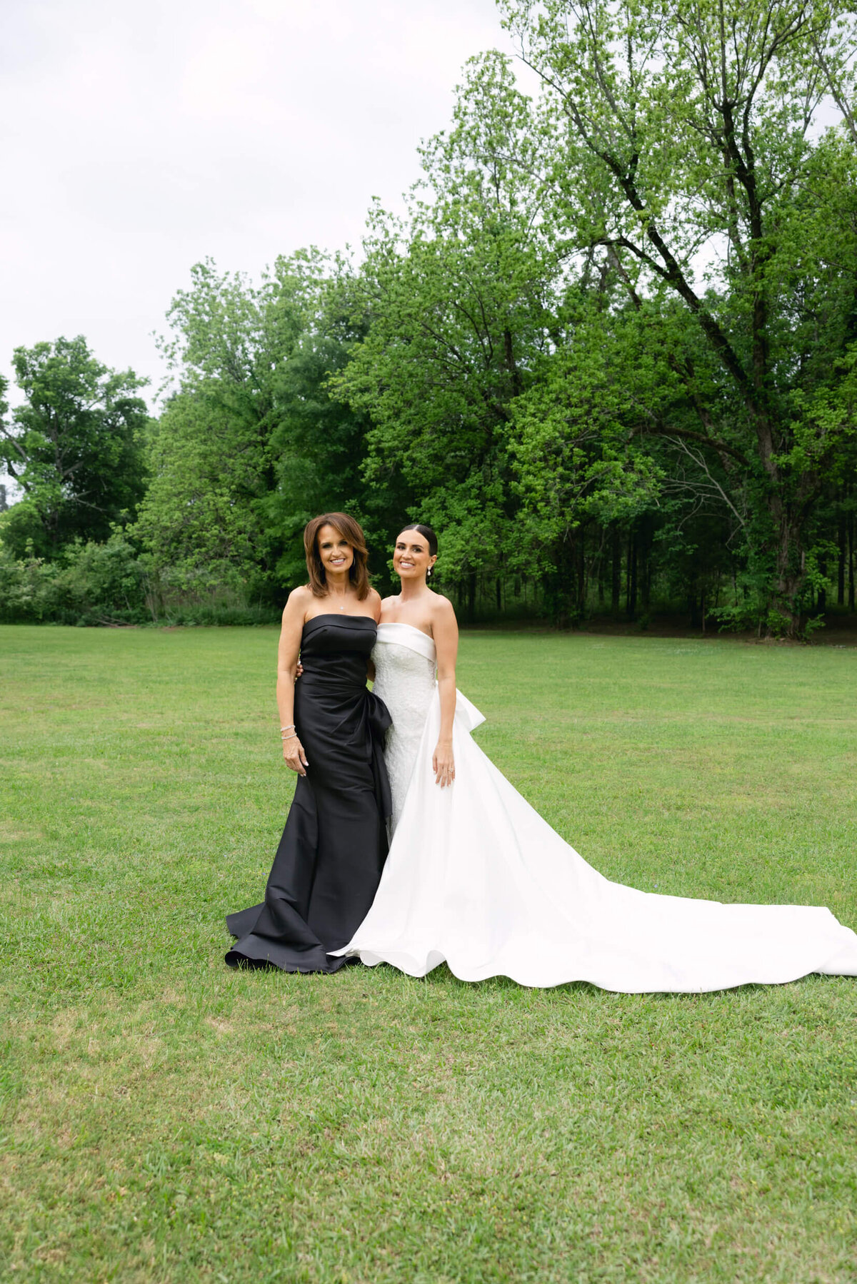 A wedding day portrait photo of the bride in her white wedding dress with her mom