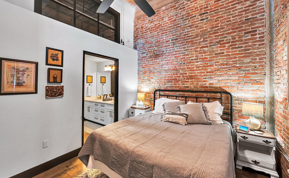 Spacious bedroom with comfortable bedding in this three-bedroom, two-bathroom industrial vacation rental loft with free WiFi, skyline view, and fully stocked kitchen in downtown Waco, Tx