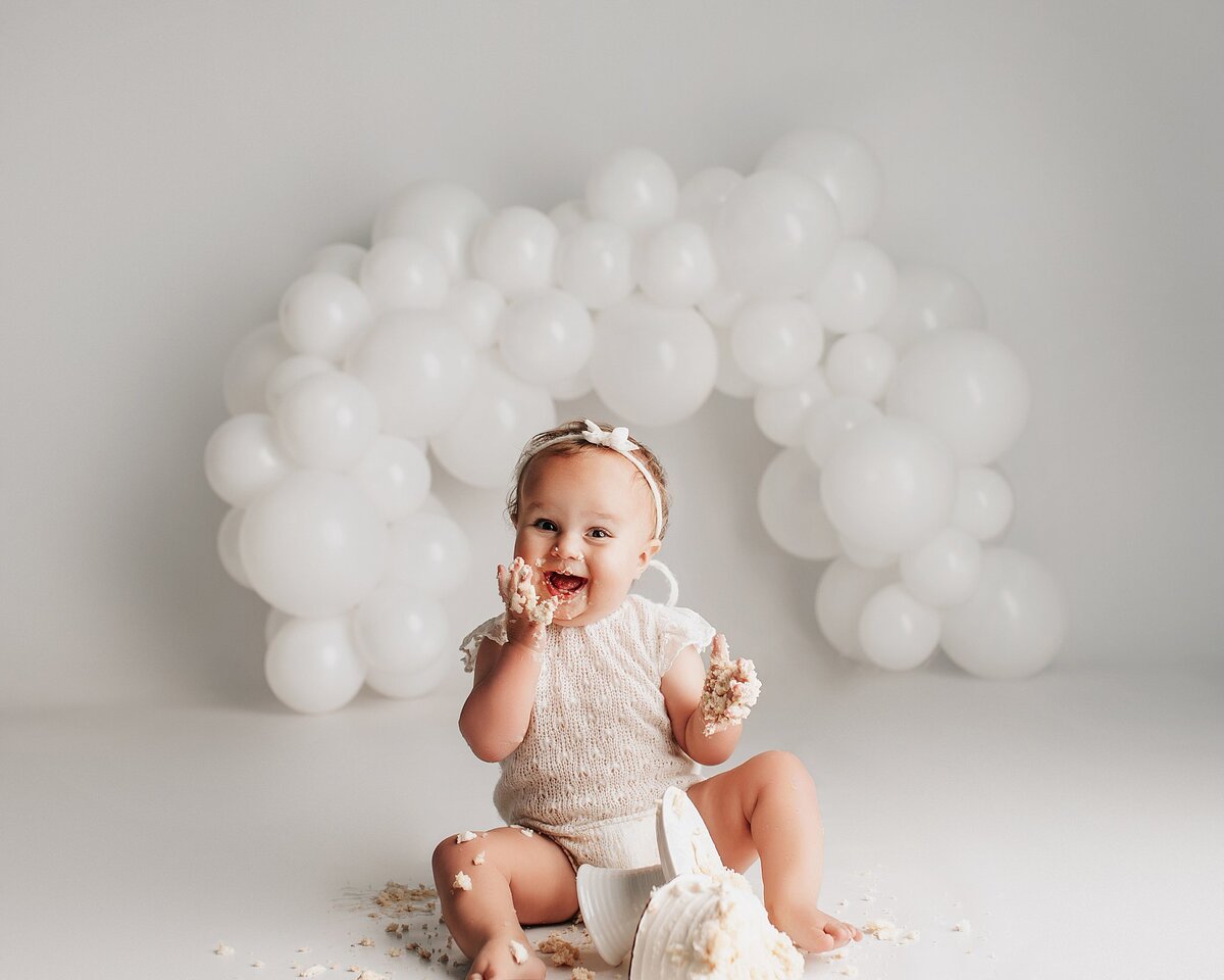 Baby reaching toward cake during first birthday photo session