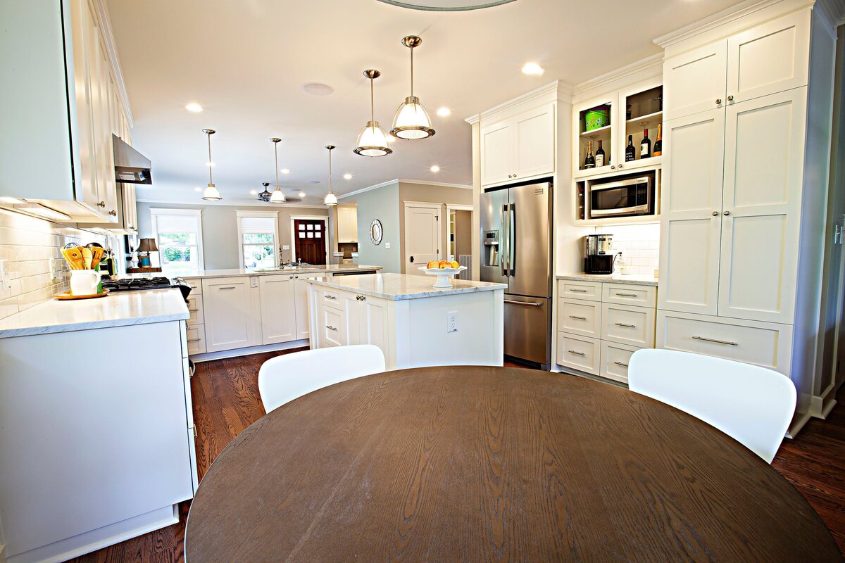 round kitchen table in updated kitchen with white cabinetry and hanging lights