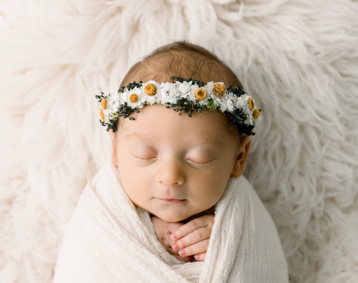 Newborn baby girl wrapped with a daisy headband