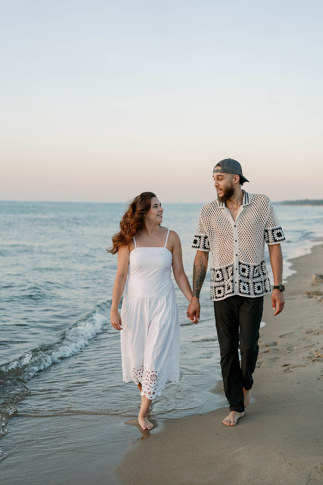 Engagement photo of couple standing in the dunes overlooking Lake Michigan at New Buffalo Beach
