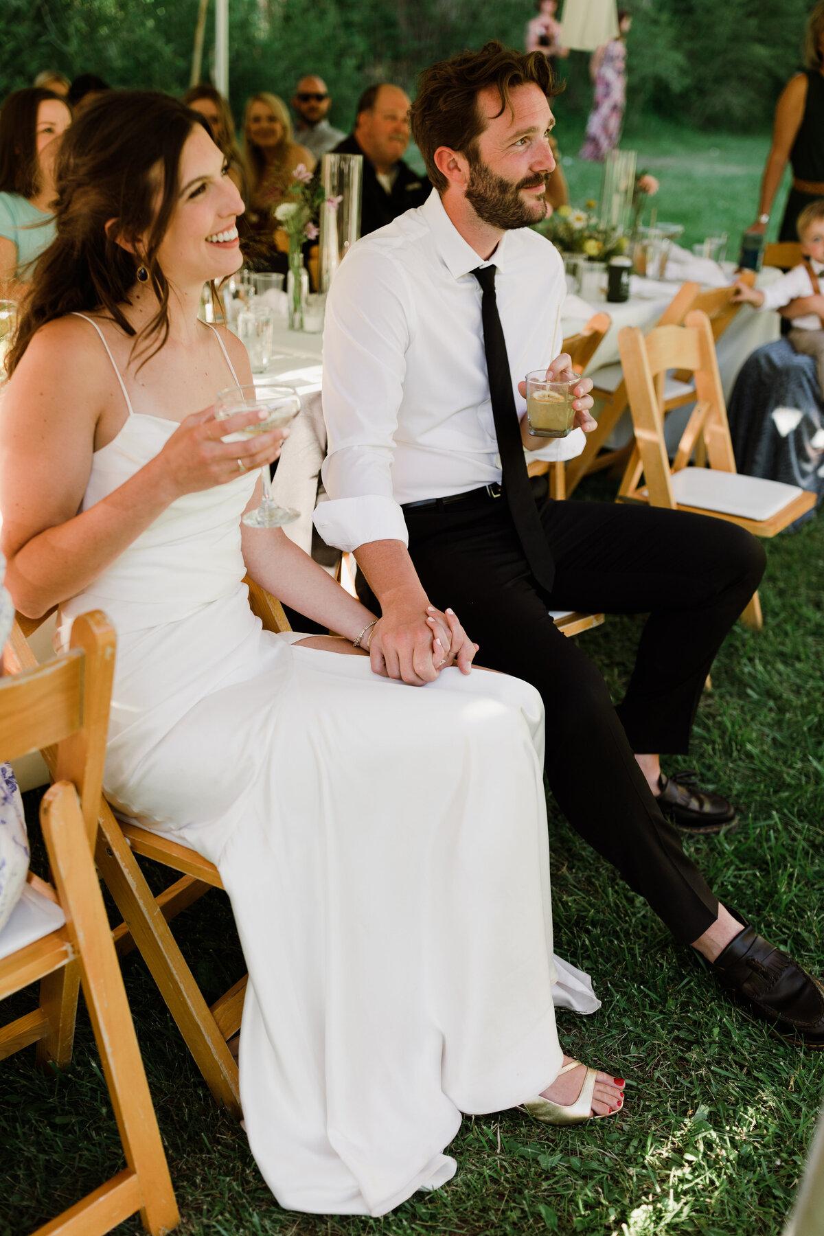 Bride and groom sitting down holding hands at Dallenbach Ranch Wedding reception Colorado