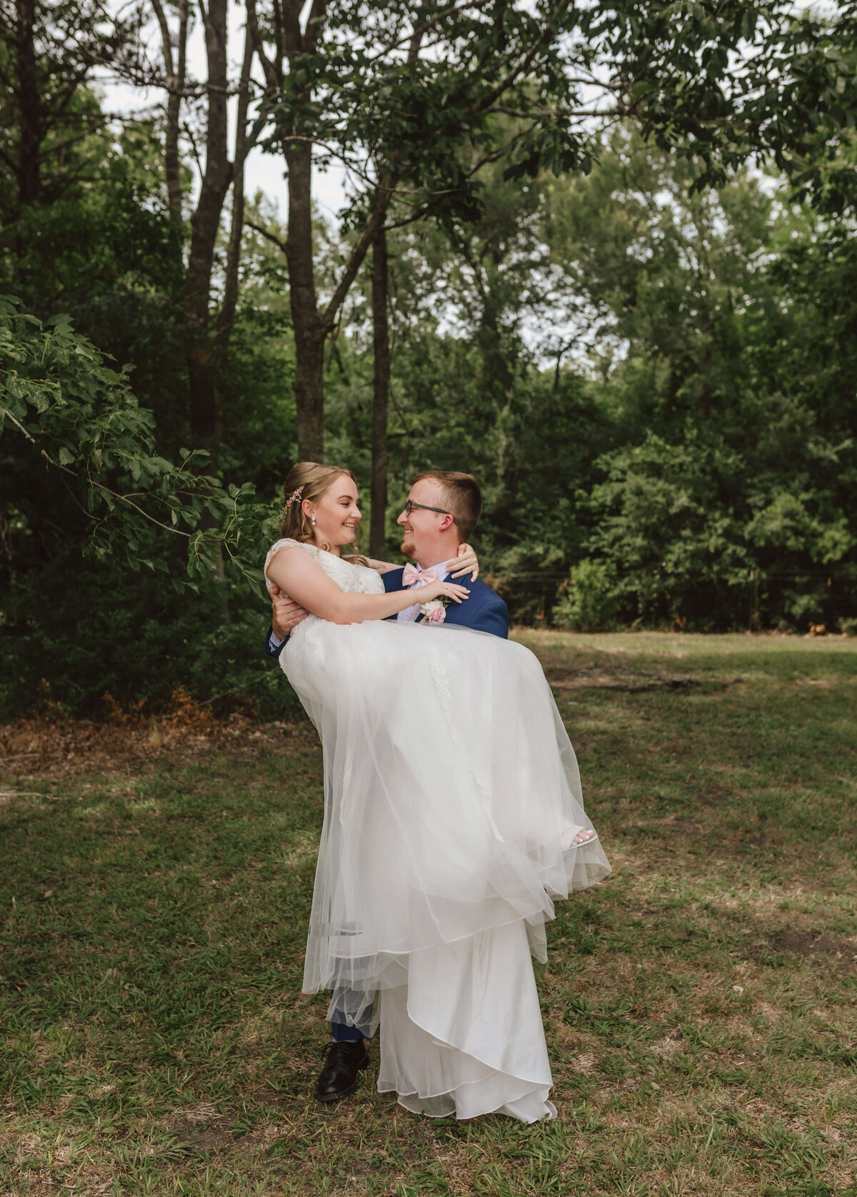 groom picks up bride and smiles lovingly after intimate wedding ceremony