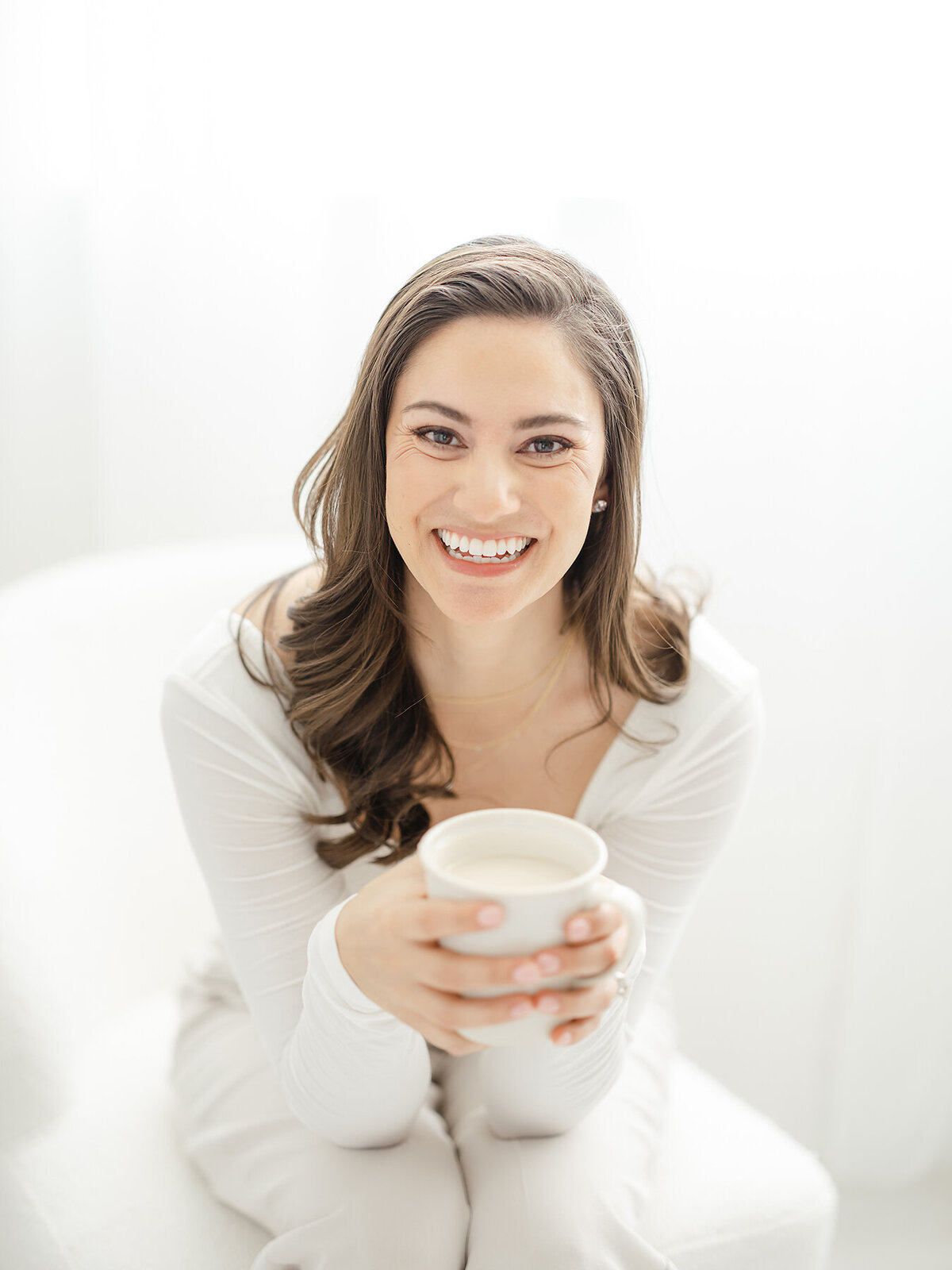 DFW business owner professional headshot of her sitting down holding a coffee mug smiling at the camera.