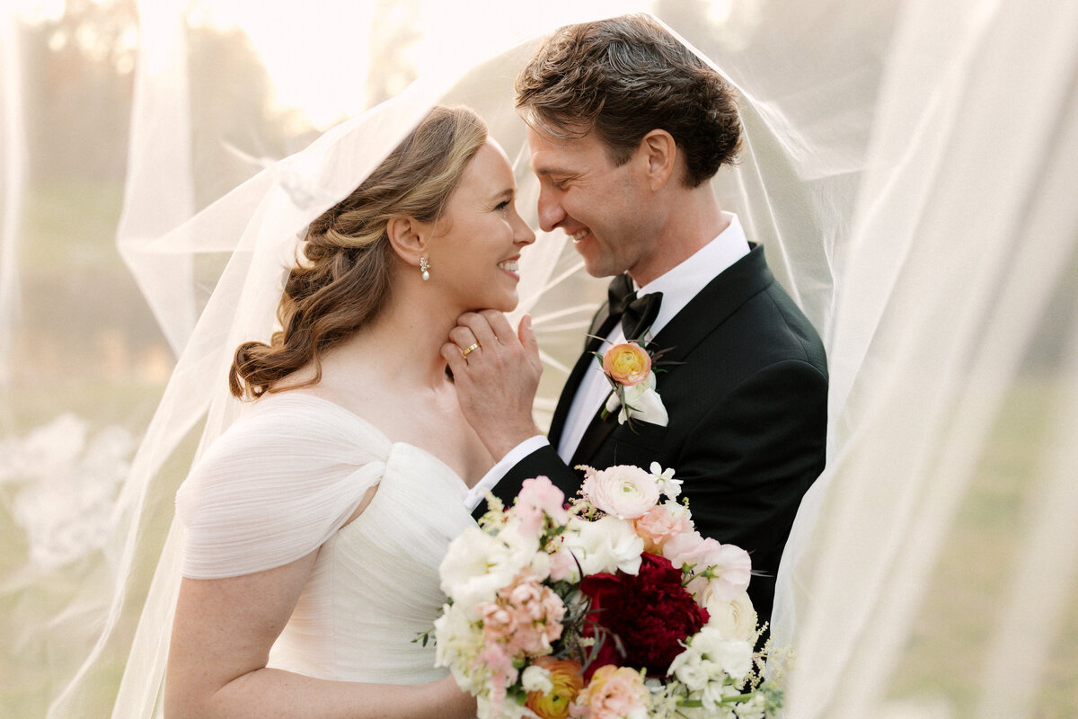 November wedding at Graylyn Estate, designed and planned by Charming Carolina — intimate sunset photo of the bride and groom smiling at each other under the bride’s veil.