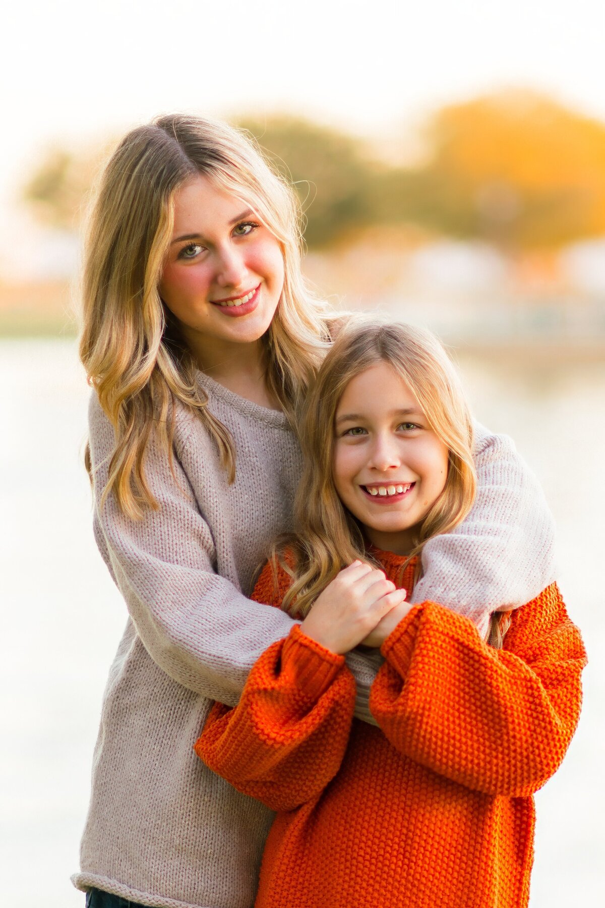two sisters smiling at the camera holding onto each other