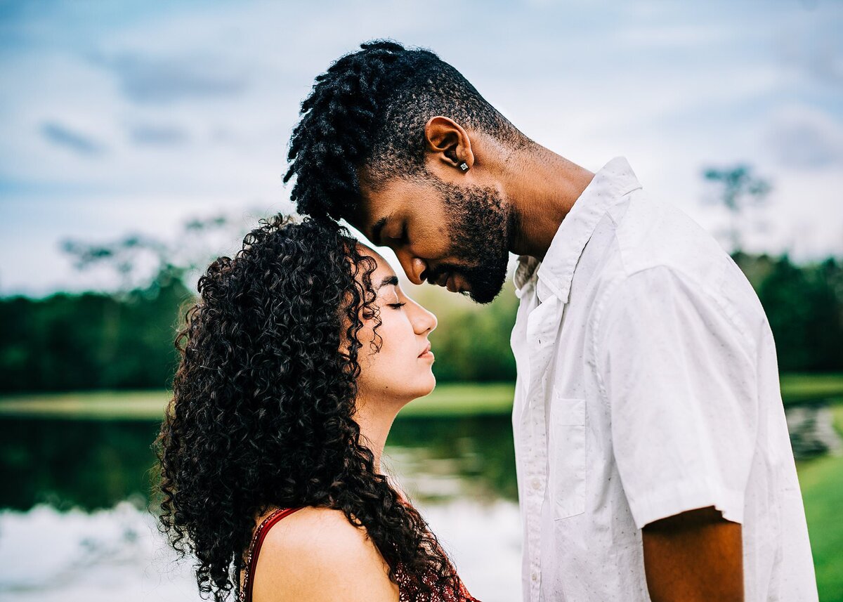 Interracial couple facing each other with foreheads almost touching and eyes closed