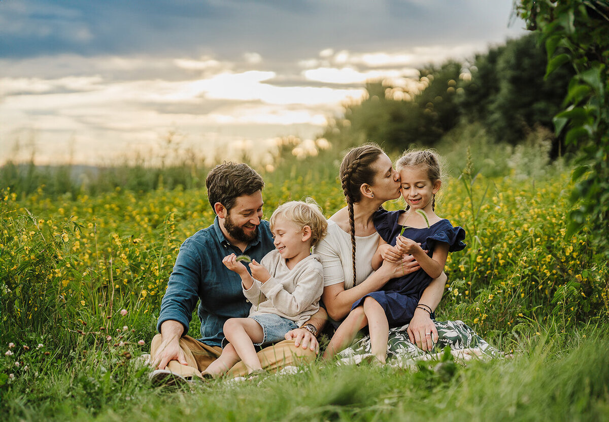 family snuggles their two young children in a field of wildflowers during boston family photos