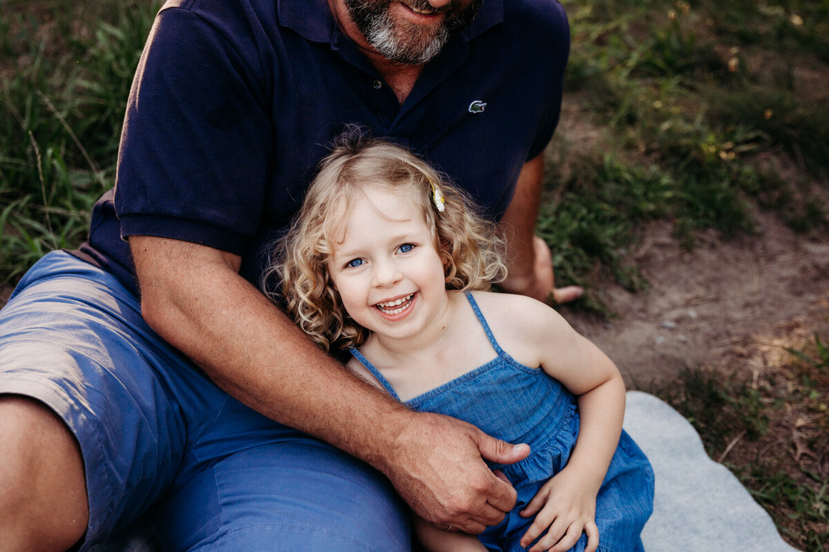 Close up of little blond girl smiling next to her dad during her family photography session