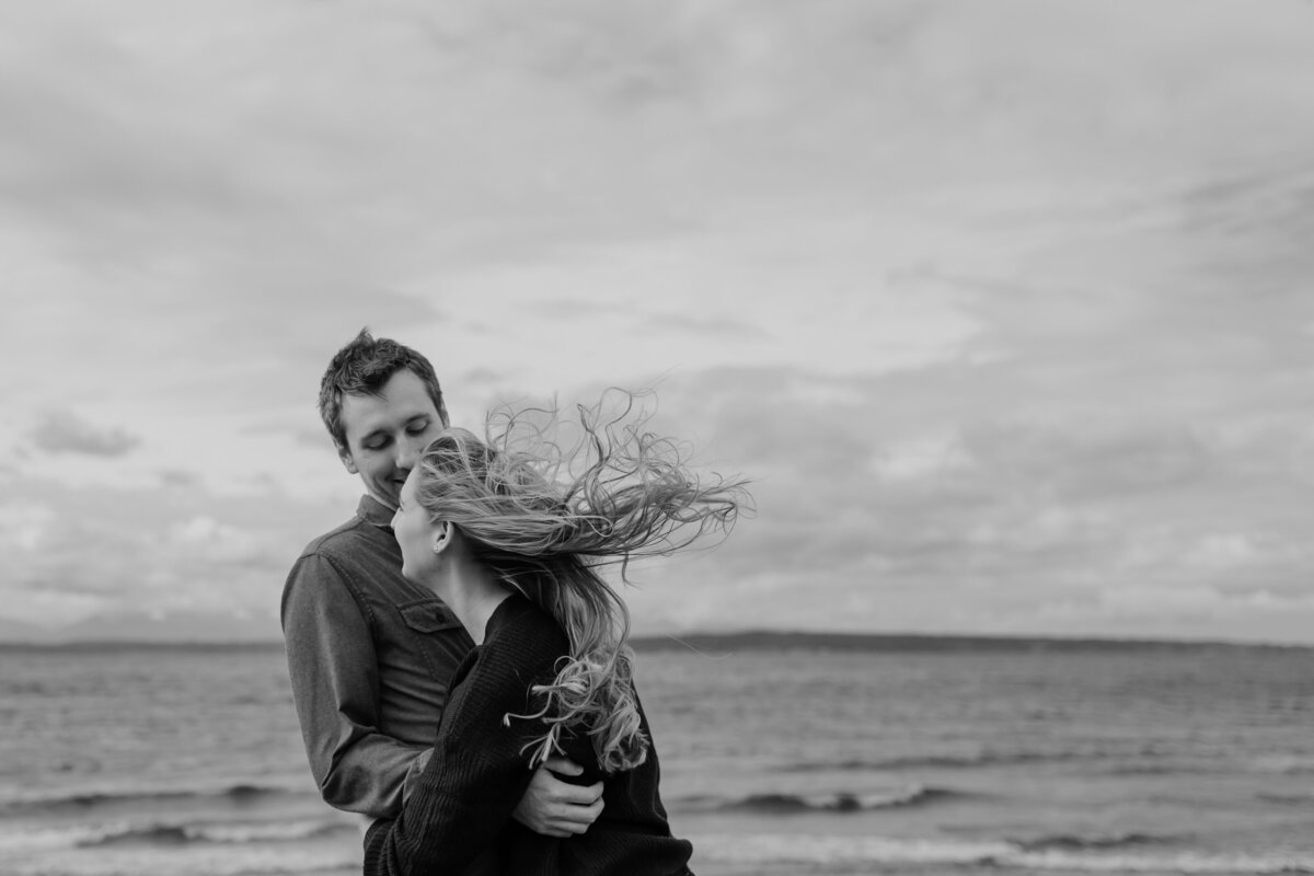 A windy and playful engagement session at a beach captured by Fort Worth wedding photographer, Megan Christine Studio