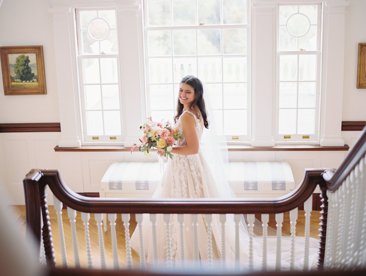 Bride at bottom of staircase at The Inn at Burklyn