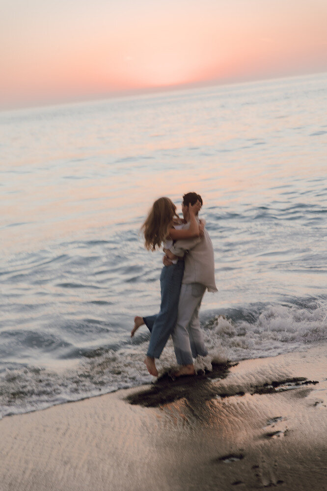 engaged couple dancing on the beach at sunset