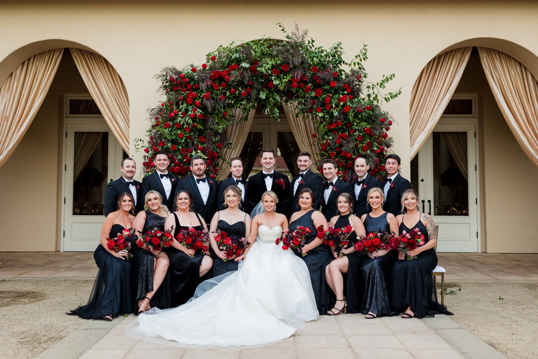 Bridal party, black bridesmaids dresses, red floral arch, ball gown, large wedding arch, phantom of the opera wedding theme, formal wedding 