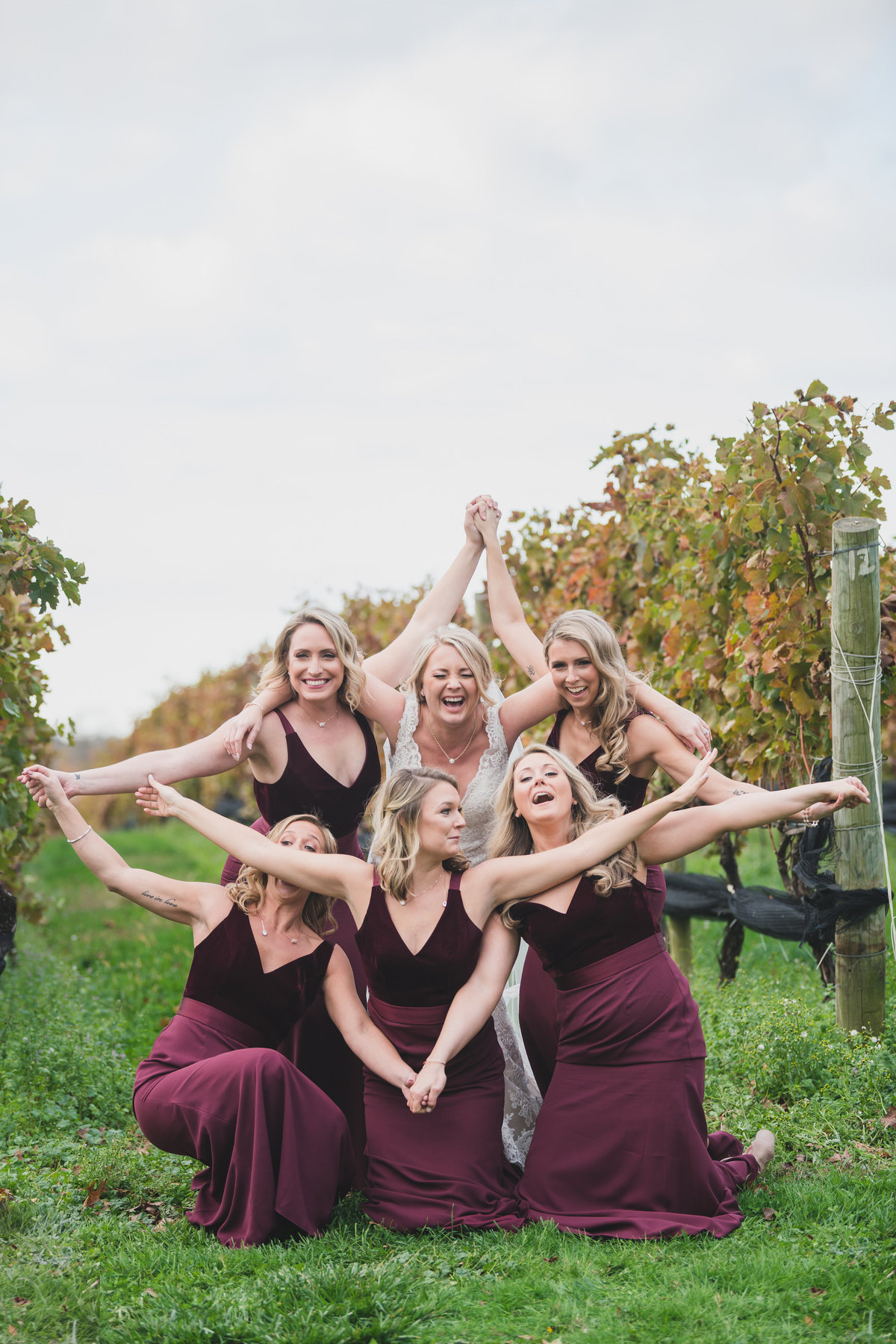 bride laughing with bridesmaids posing at vineyards from wedding at The Vineyards at Aquebogue