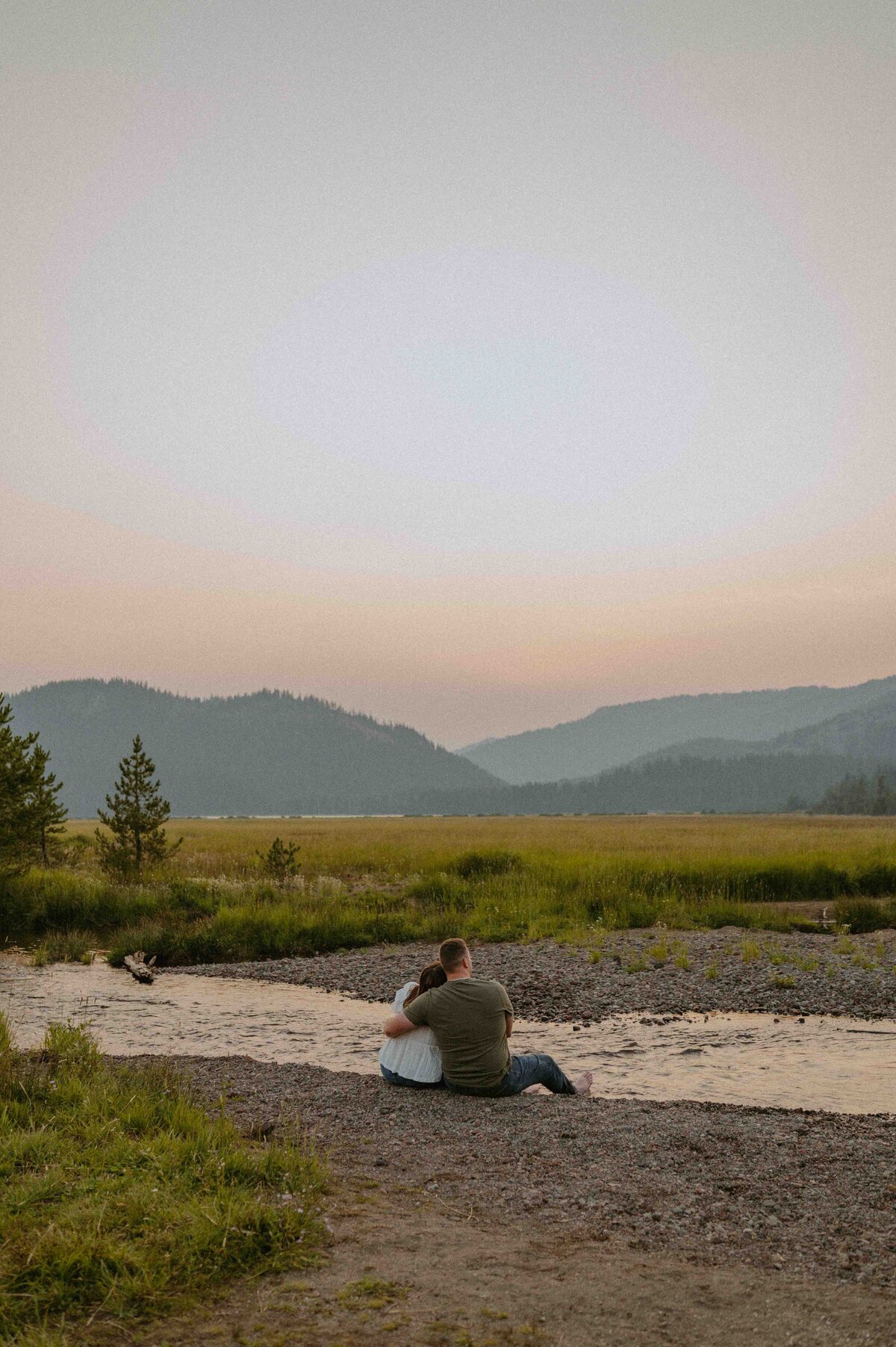 sitting side by side near the river enjoying the sunset