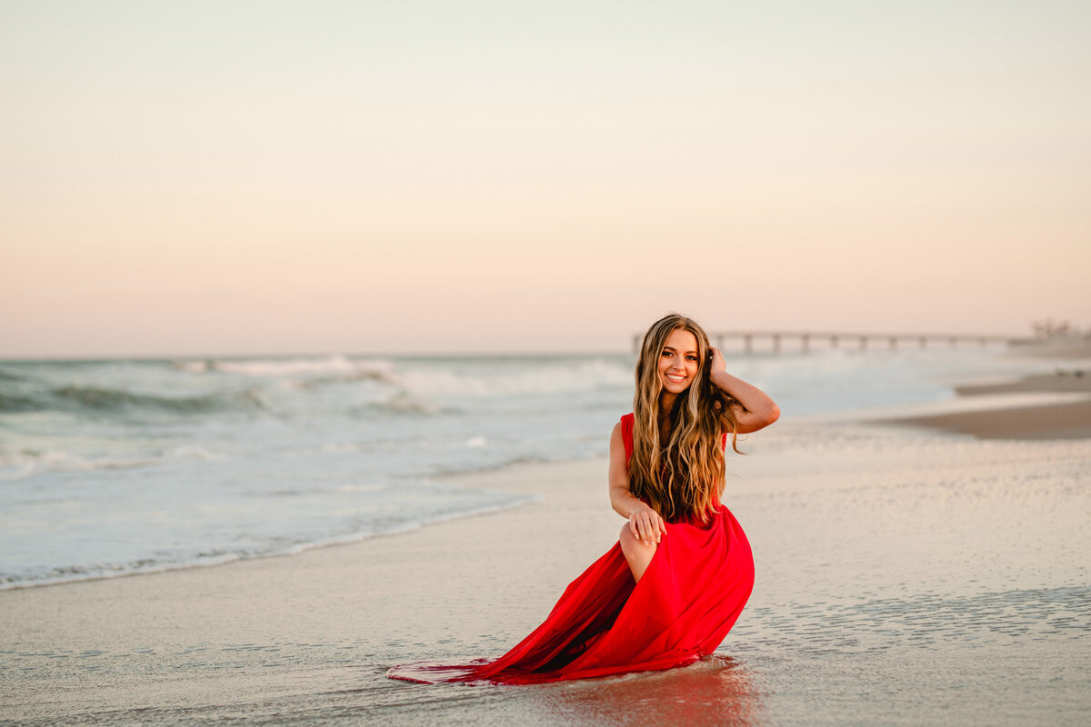 St Augustine beach senior photographer. Girl on beach with beautiful cotton candy sunset.