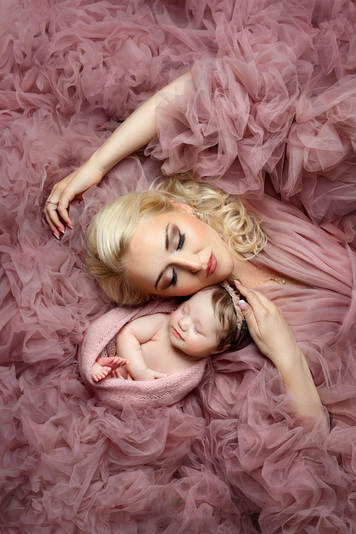 newborn baby girl in a pink wrap laying with her mom in a pink tulle dressnewborn baby girl in a pink wrap laying with her mom in a pink tulle dress