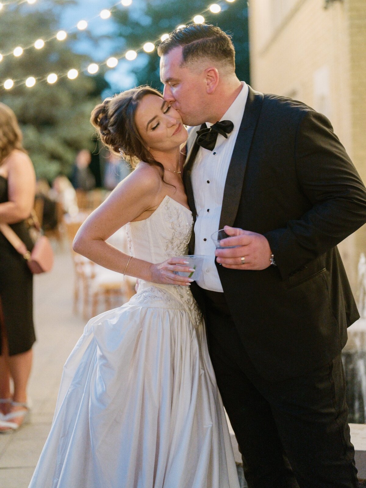 groom kissing bride on the cheek at beautiful wedding reception