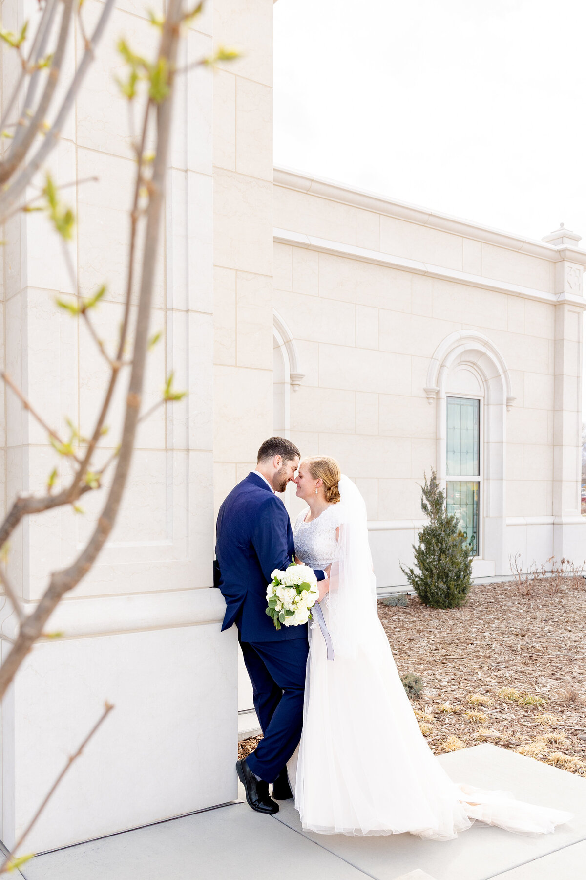 Bride and groom embracing and sharing a quiet moment beside the Taylorsville Utah Temple.