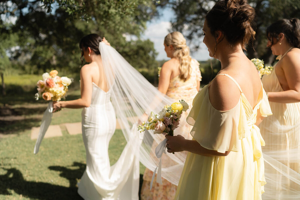 bridesmaids leading the bride while they hold her veil