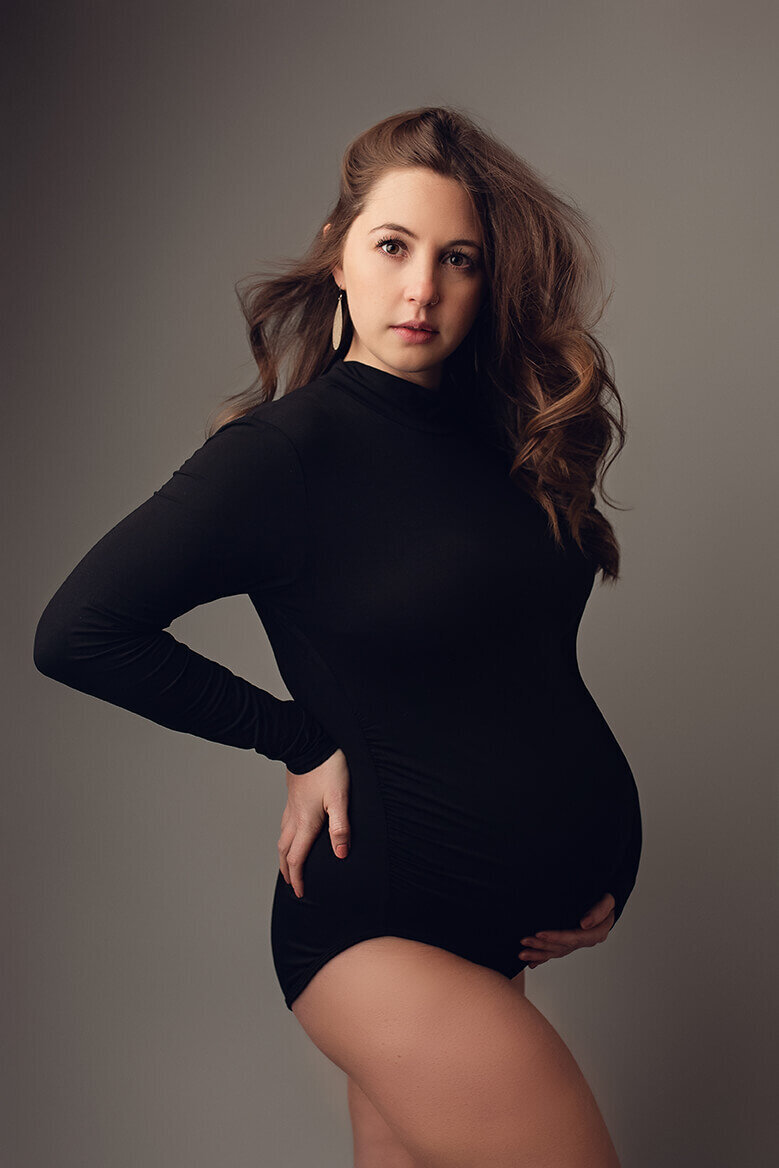 pregnant woman holding her back and her bump in a black body suit