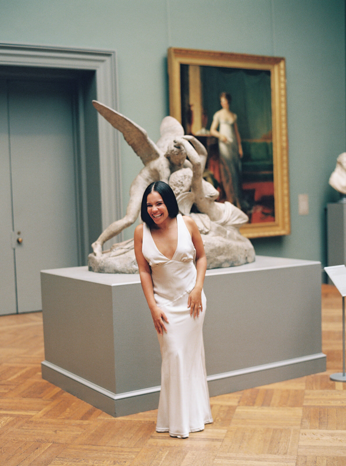 bride laughing with a statue and art behind her